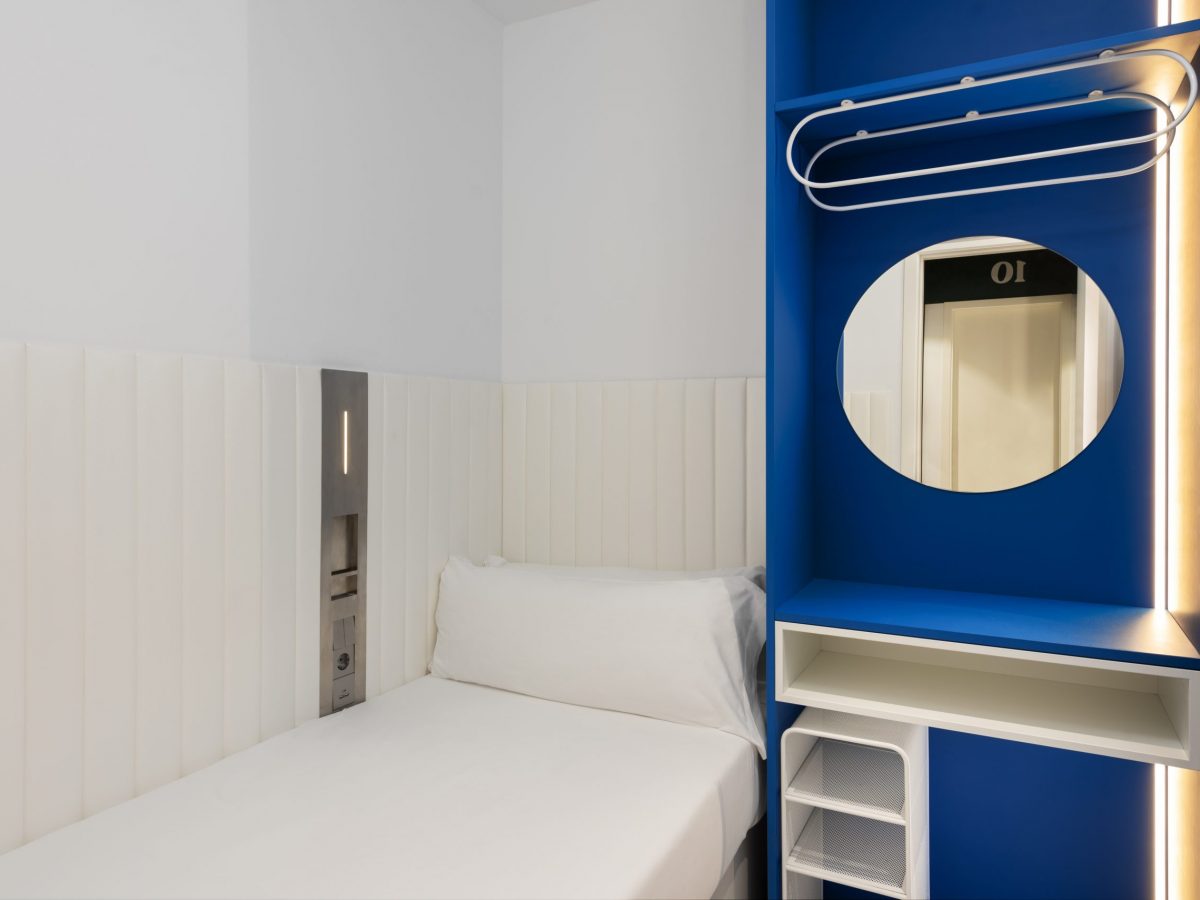 Bed with white sheets and a blue table at a Malaga hostel